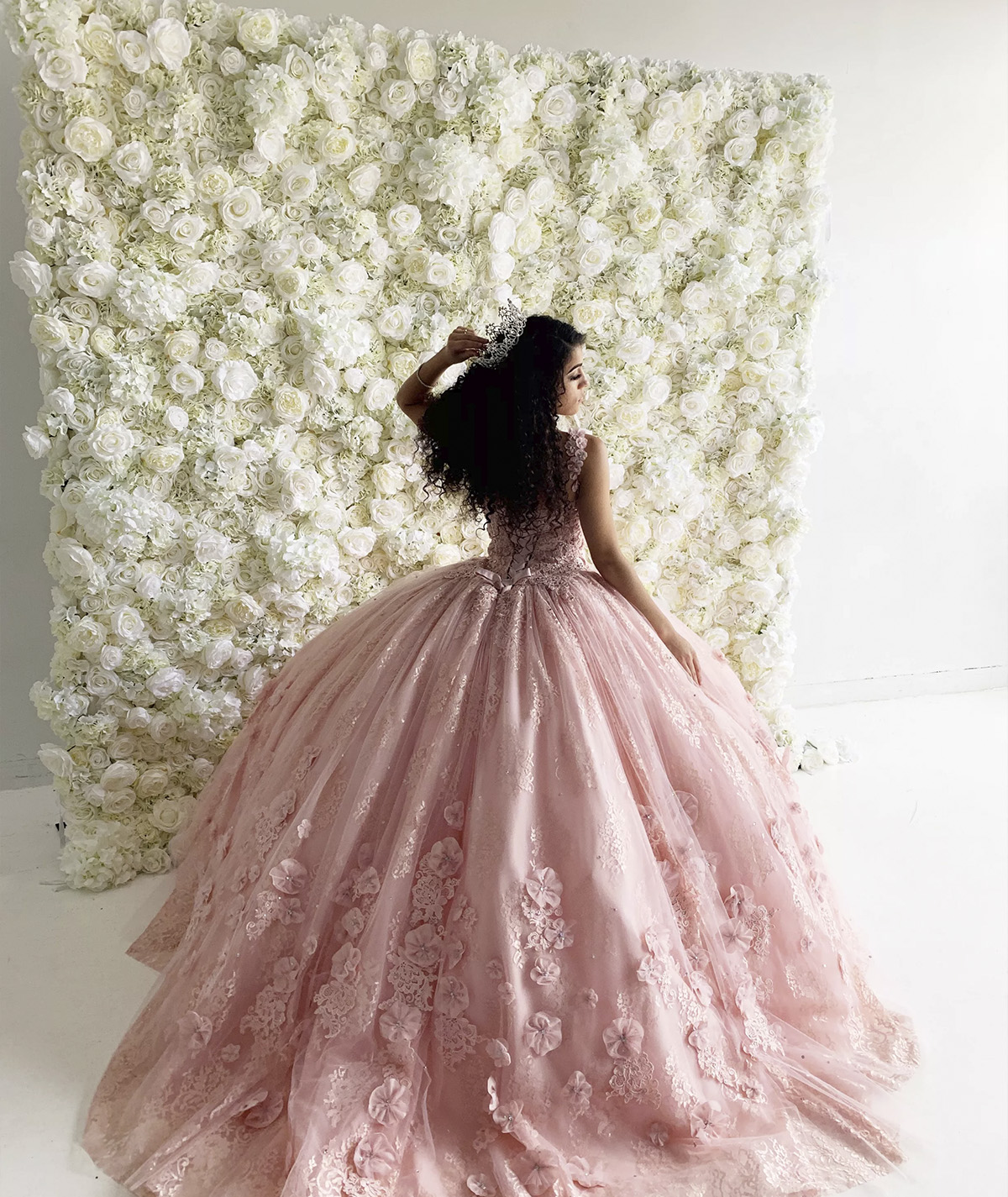 Flower wall backdrop with a girl posing in front for her sweet 16