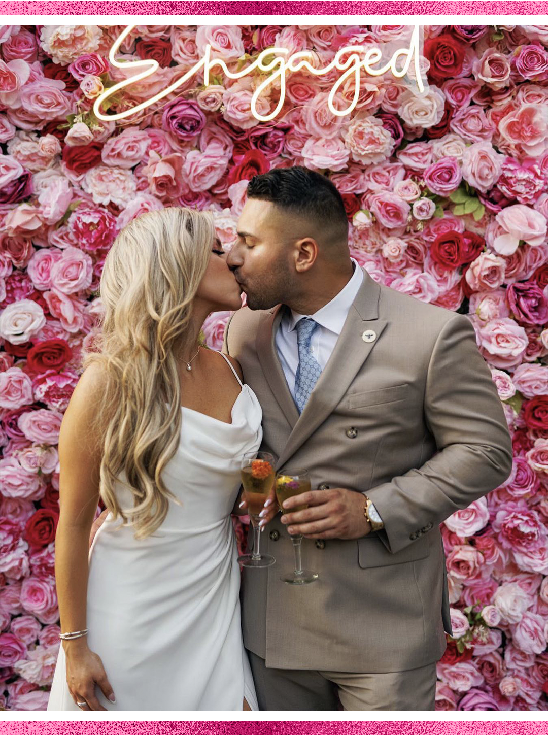 Pink flower wall rental with neon sign rental and couple kissing in front of it.